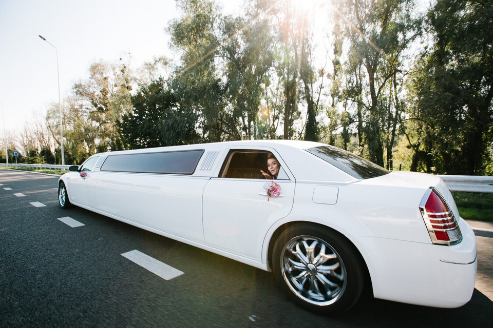 Długa biała limuzyna udekorowana do ślubu.